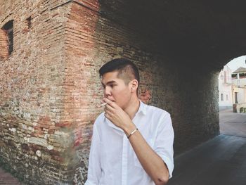 Young man standing against brick wall