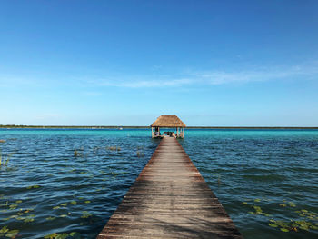 Pier over sea against blue sky