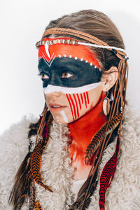 Woman with face paint looking away against white background