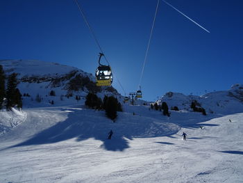 Ski lift over snowcapped mountains against clear blue sky