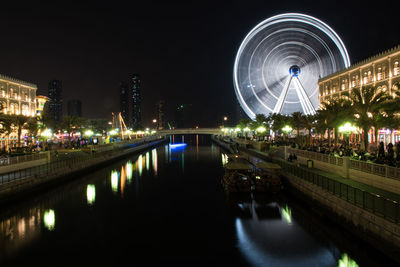 Illuminated bridge over river against sky at night