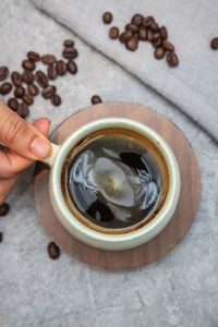 Cropped hand of person holding coffee on table