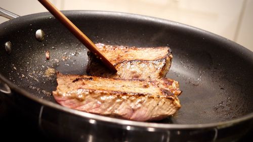 Close-up of steak cooking on frying pan at home