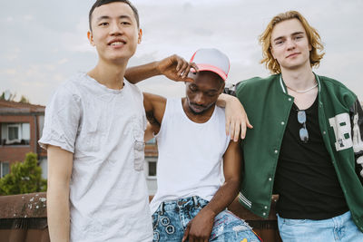 Portrait of smiling young men with friend wearing cap