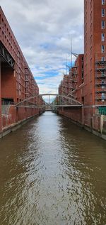 Bridge over canal amidst buildings against sky in city