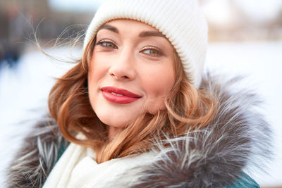 Portrait of smiling young woman wearing knit hat standing outdoors