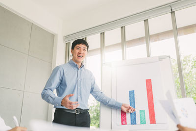 Young man smiling while standing against window