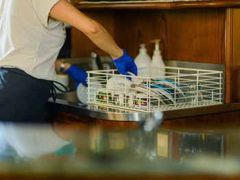 Female bar tender barista washing and cleaning cups and dishes