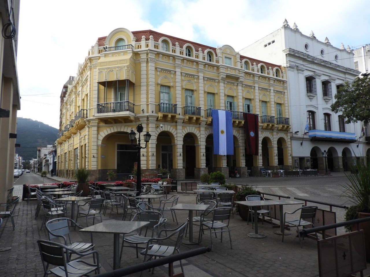 architecture, building exterior, built structure, chair, seat, table, sky, building, cafe, city, sidewalk cafe, restaurant, cloud - sky, incidental people, absence, day, nature, business, outdoors, setting