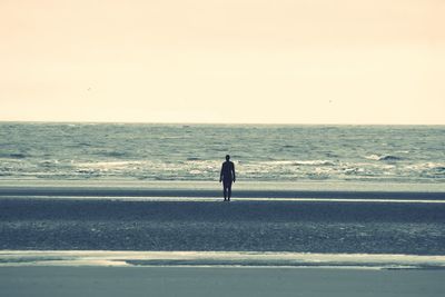 Silhouette man standing on beach against clear sky