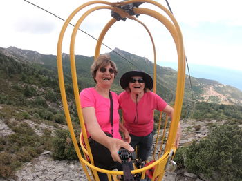 Senior women enjoying cable car ride in yellow basket from the top of elba island