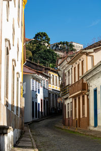 Street amidst buildings against clear blue sky