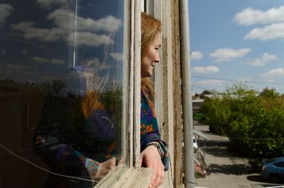 Side view of young woman looking away against sky