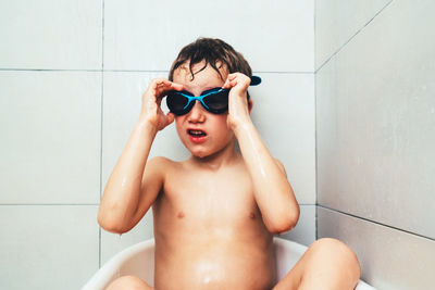 Shirtless boy wearing swimming goggles in bathroom