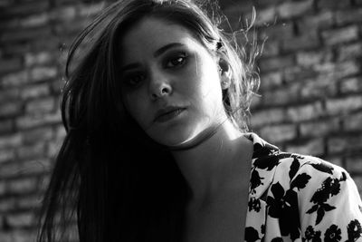 Portrait of confident woman standing against brick wall