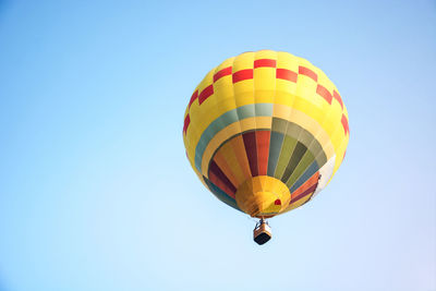 Low angle view of yellow hot air balloon flying against clear sky