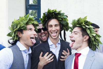 Playful friends wearing leaves on heads against wall