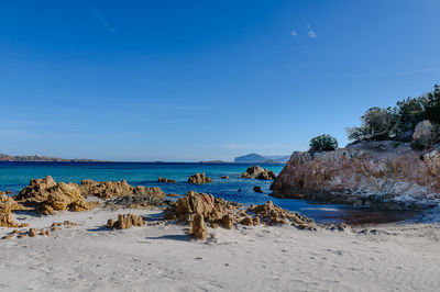 Rocks on beach against blue sky