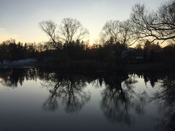 Reflection of silhouette trees in lake against sky