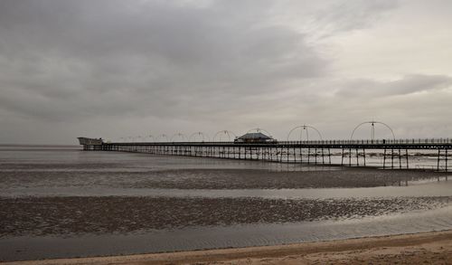 Pier on beach against sky