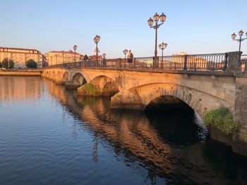 Arch bridge over river against sky in city