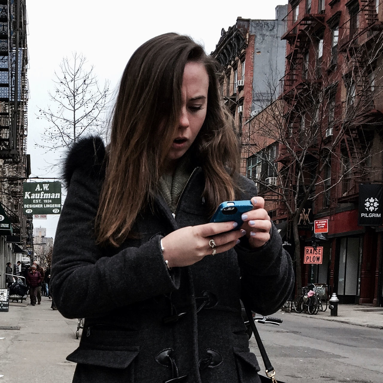 building exterior, lifestyles, young adult, casual clothing, leisure activity, built structure, architecture, city, person, young women, waist up, standing, three quarter length, long hair, holding, front view, focus on foreground, side view