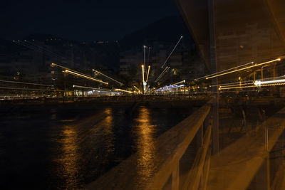 Illuminated bridge over river against sky at night