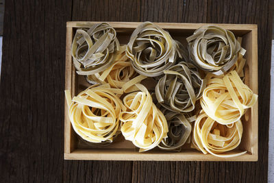 Directly above shot of tagliatelle pasta in crate on table