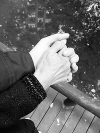 Cropped image of couple holding hands on pier by sea