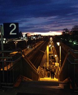 Illuminated railroad tracks against sky at night