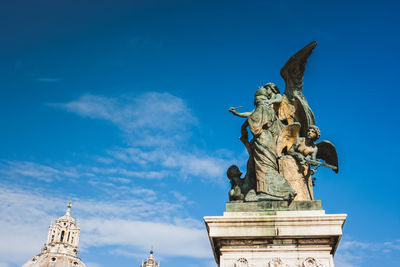 Low angle view of angel statue against blue sky