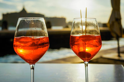 Close-up of wineglass on table against sky during sunset