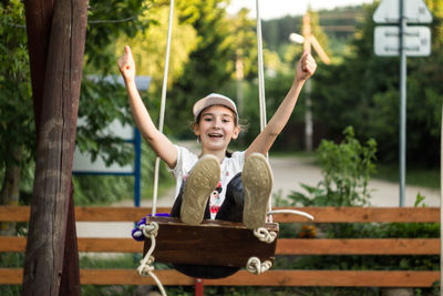 Full length portrait of happy girl enjoying on swing at park