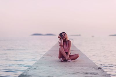 Young woman on beach against clear sky