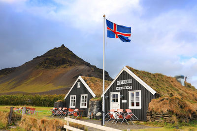 Flag on house by mountain against sky