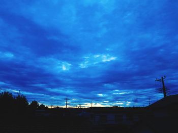 Low angle view of silhouette buildings against blue sky