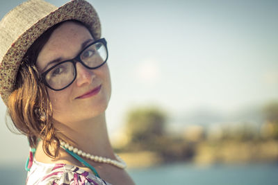 Side view portrait of smiling woman wearing eyeglasses and hat against sky