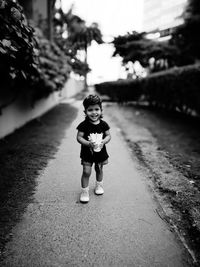 Full length of girl holding drink while standing on footpath