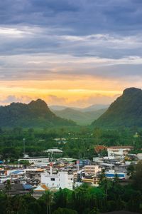 Townscape and mountains against cloudy sky during sunset