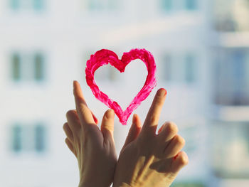 Fingers draw red heart on window sunlight. concept valentine's day, romantic, gift heart emotional