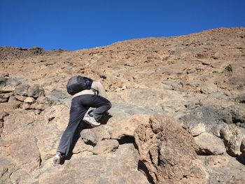 Rear view of woman on rock against sky