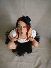 High angle portrait of woman with make-up crouching on floor