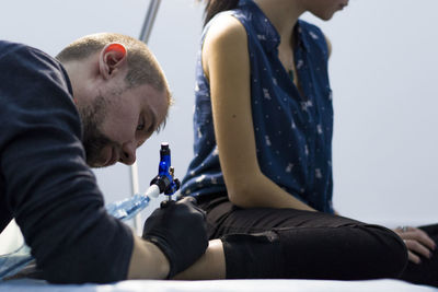 Artist making tattoo on woman leg