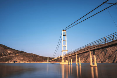 Bridge over river against clear blue sky