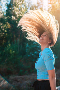 Beautiful woman tossing hair against tree
