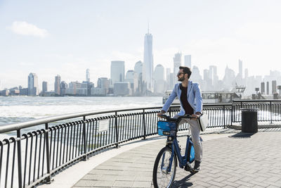 Usa, man on bicycle at new jersey waterfront with view to manhattan