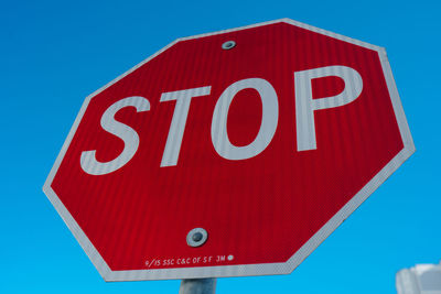 Low angle view of road sign against blue sky