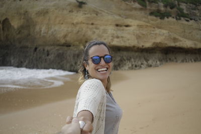 Cropped hand holding happy woman at beach