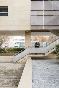 Bearded hipster man relaxing on stairs in a building complex