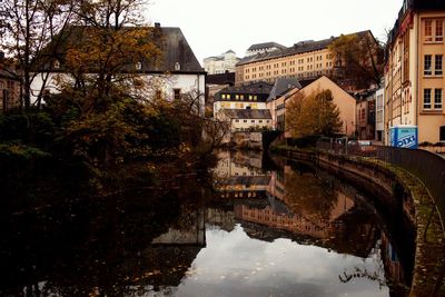 Arch bridge over river amidst buildings in city against sky